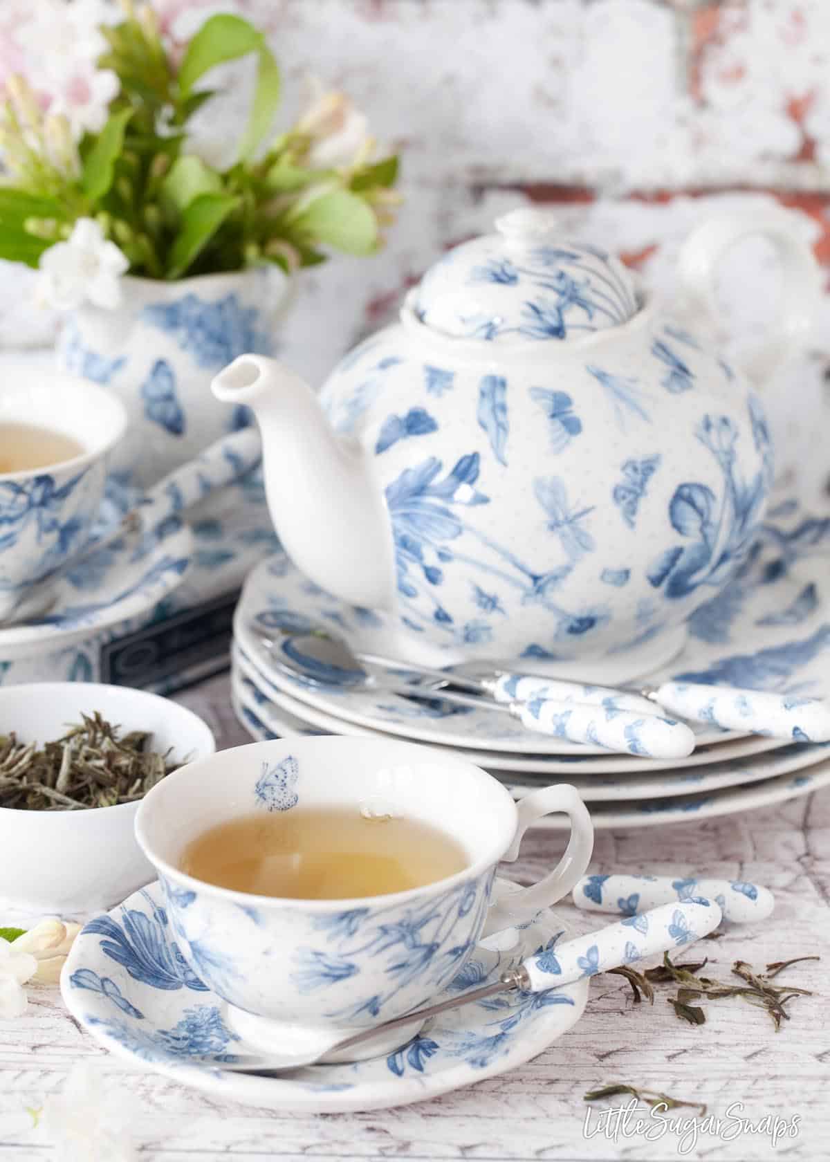 Serving afteroon tea: a cup of tea with a teapot in the background.